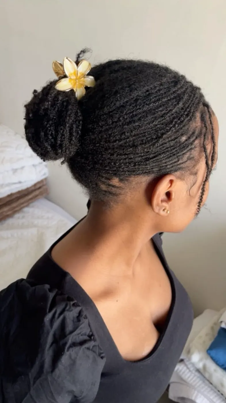 Micro locs swept into a high bun with a flower clip