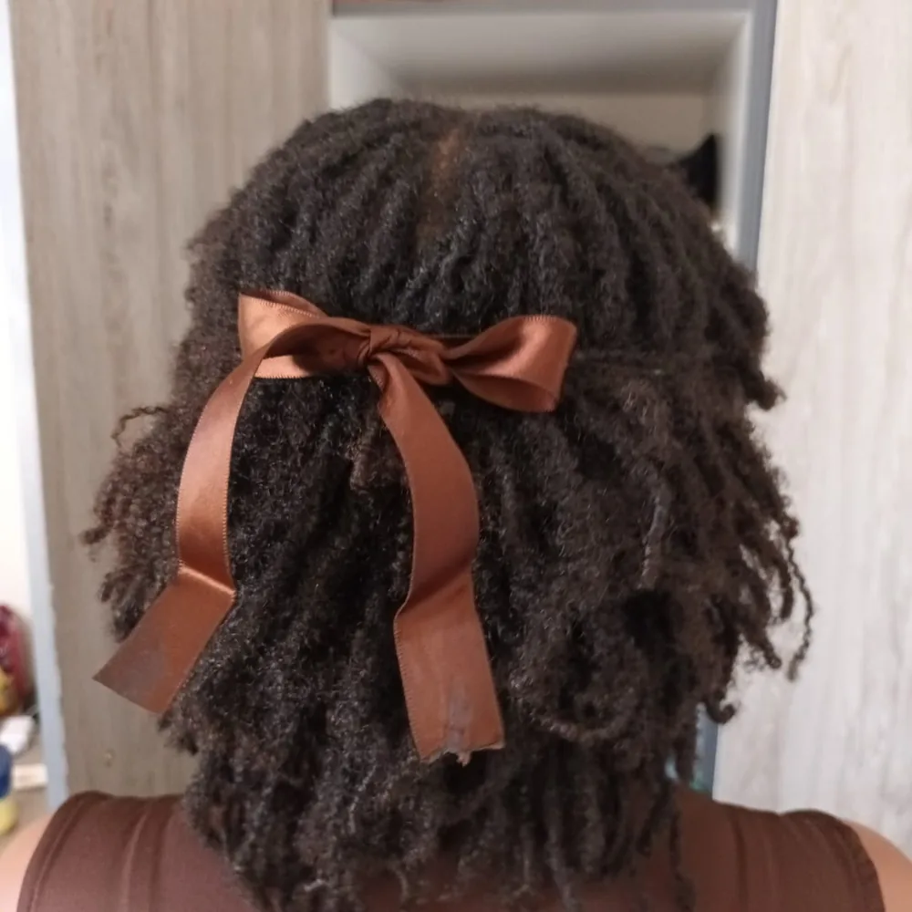 Micro locs tied back with a brown satin ribbon